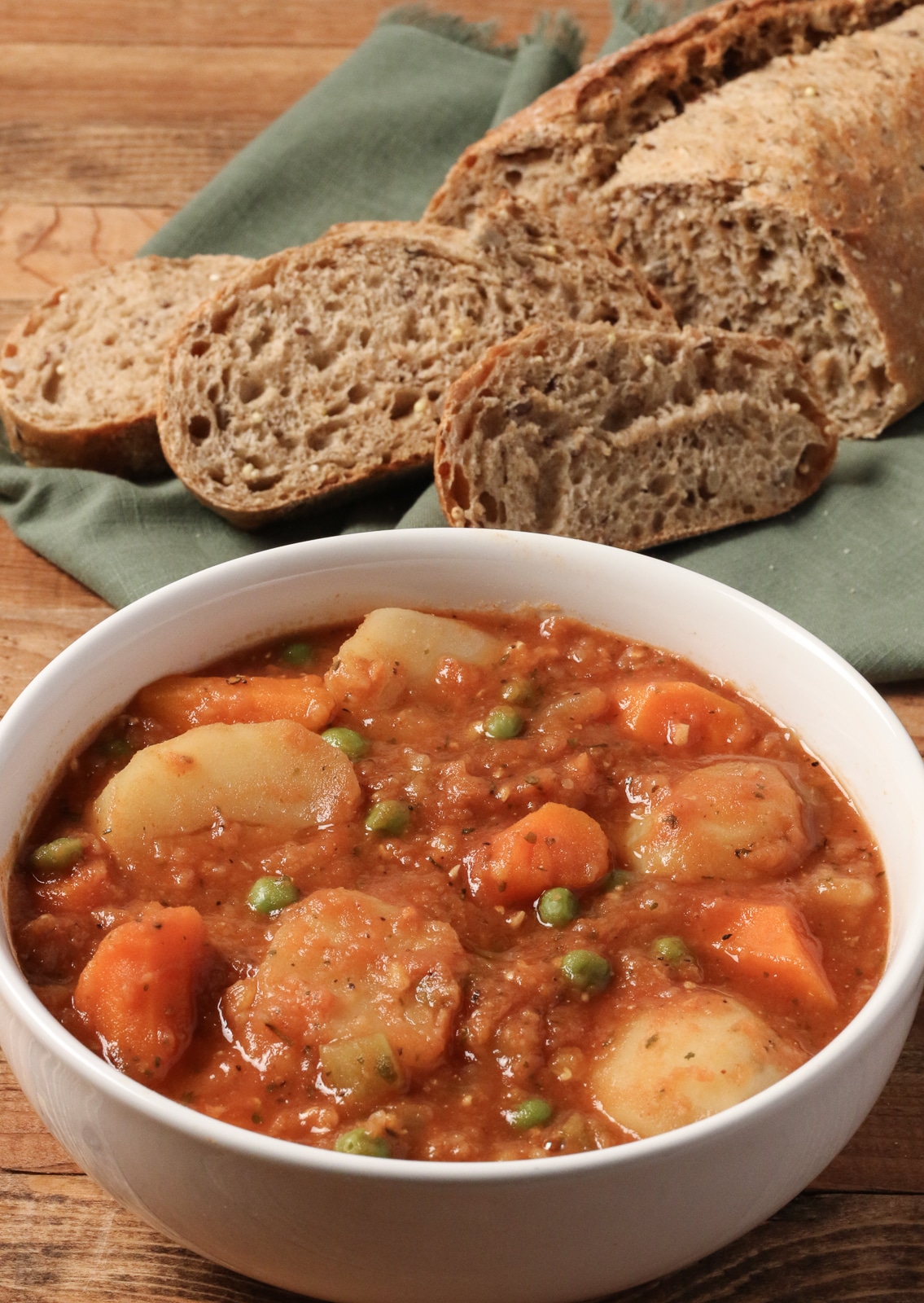 Bowl of Instant Pot Vegetable Stew with sliced whole grain bread in background