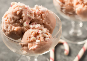 Two glass dessert dishes with Vegan Peppermint Ice Cream, with two candy canes sitting next to them