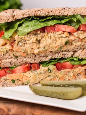 Chickpea salad sandwich on a plate with pickle spears