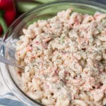 Bowl of macaroni salad with cloth napkin, red bell pepper, and celery in background