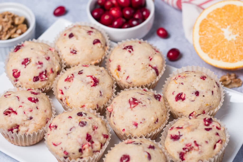 Platter of muffins with orange half, fresh cranberries, and walnuts in background