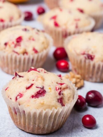 Cranberry muffins with fresh cranberries scattered around them