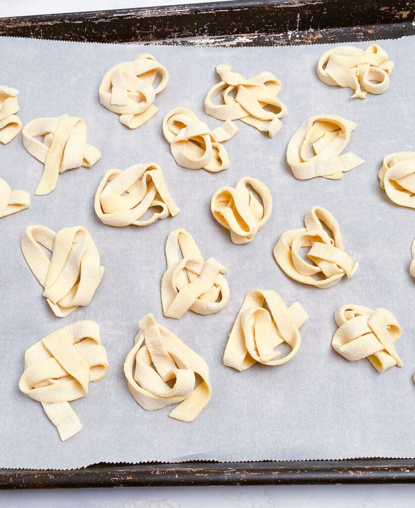 Parchment covered baking pan with fresh pasta bundles