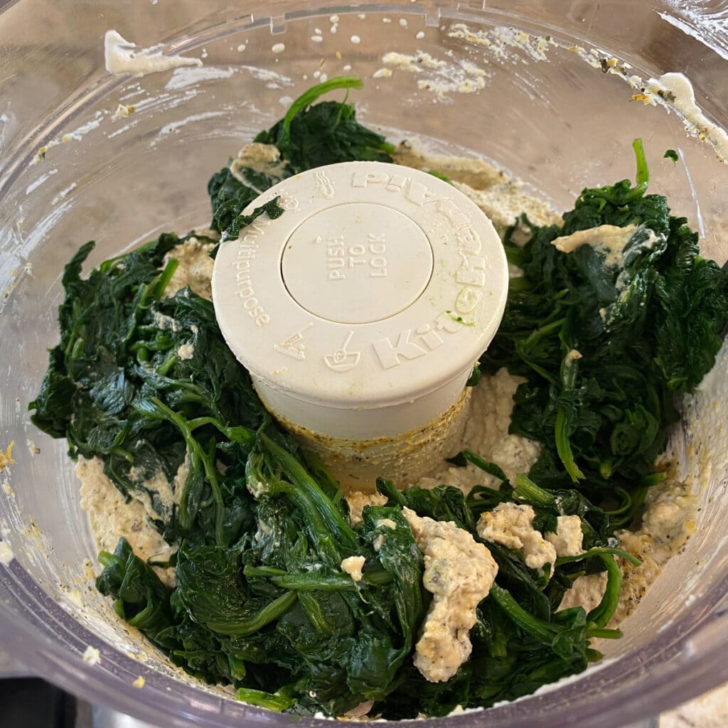 Steamed spinach added to food processor with vegan ricotta
