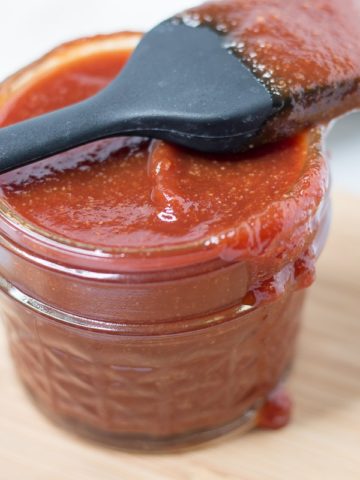 Jar of sauce with basting brush resting on top of jar