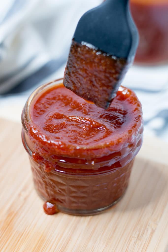 Basting brush dipping into jar of bbq sauce