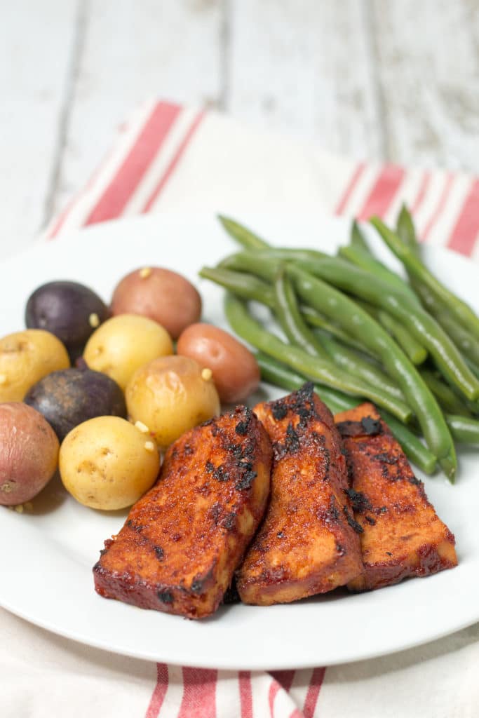 White plate with bbq tofu, baby potatoes, and green beans