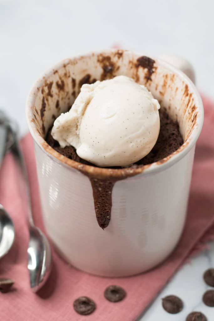 Mug cake in a pink mug topped with scoop of vanilla ice cream