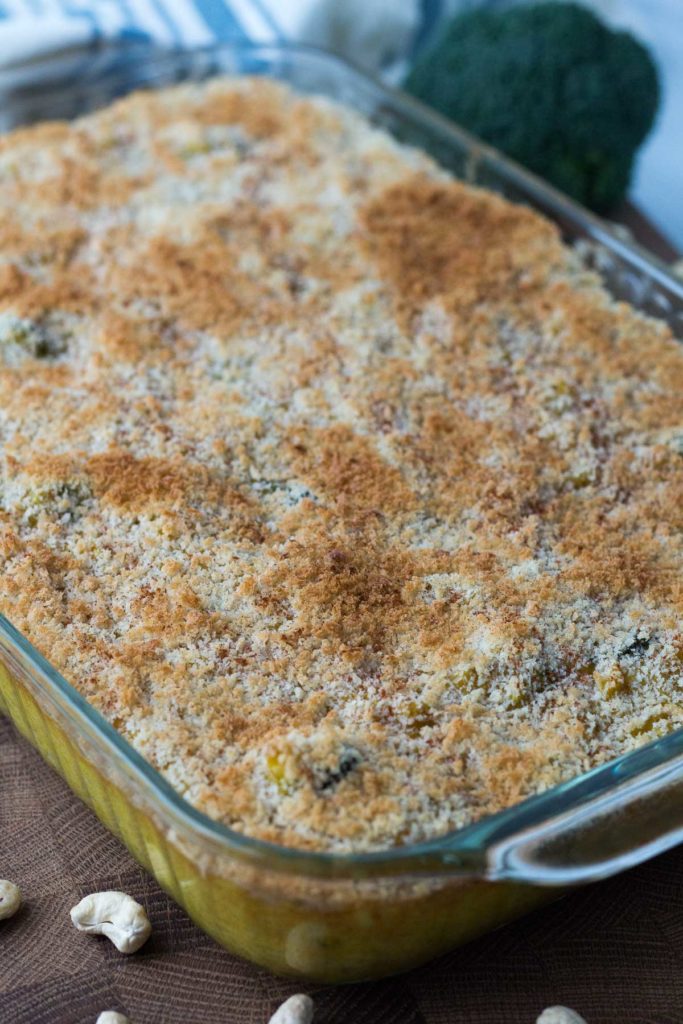 Glass pan of broccoli rice casserole on wooden cutting board
