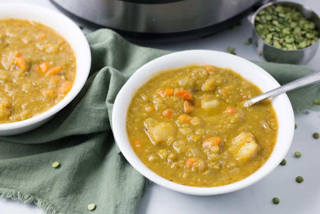 Two bowls of split pea soup in front of Instant pot and cup of split peas