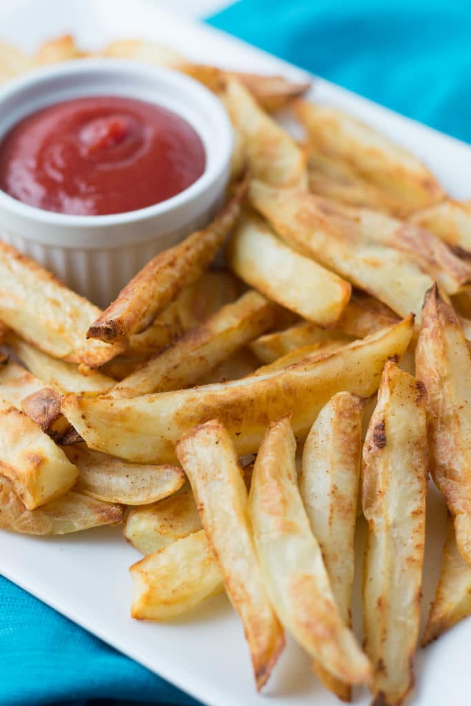 White platter with homemade baked french fries and cup of ketchup