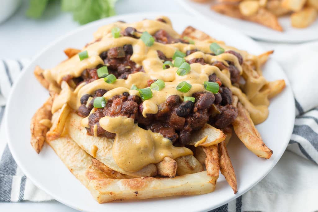 Vegan chili cheese fries on a white plate