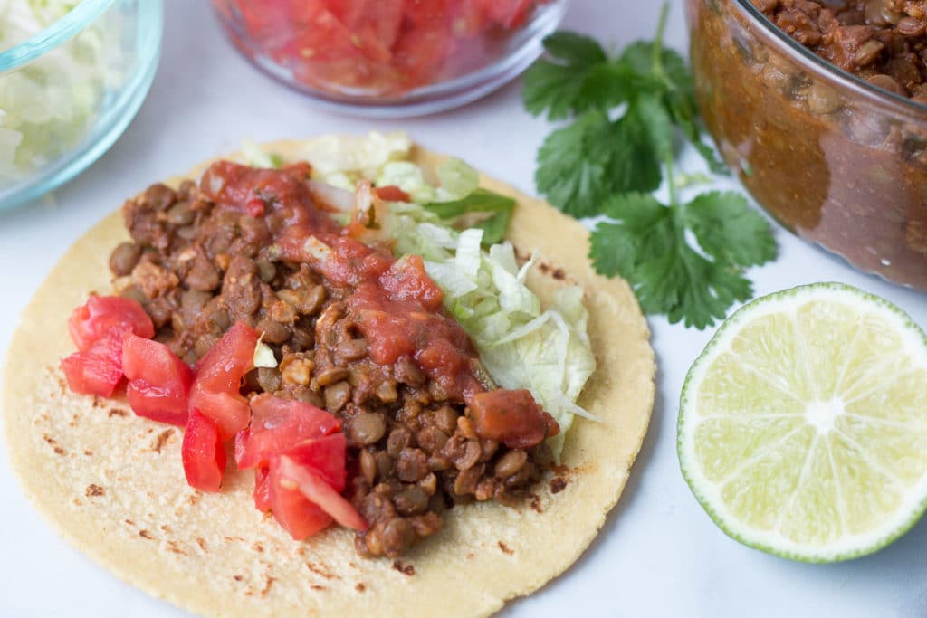 Open face lentil walnut taco surrounded by taco ingredients