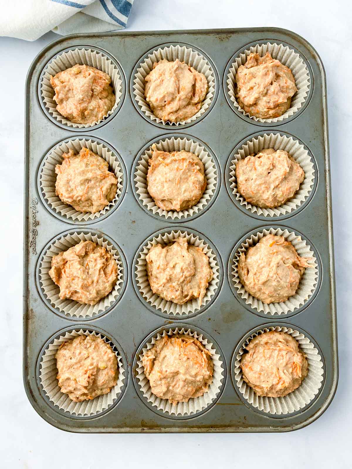 Muffin batter in cupcake pan lined with parchment baking papers.