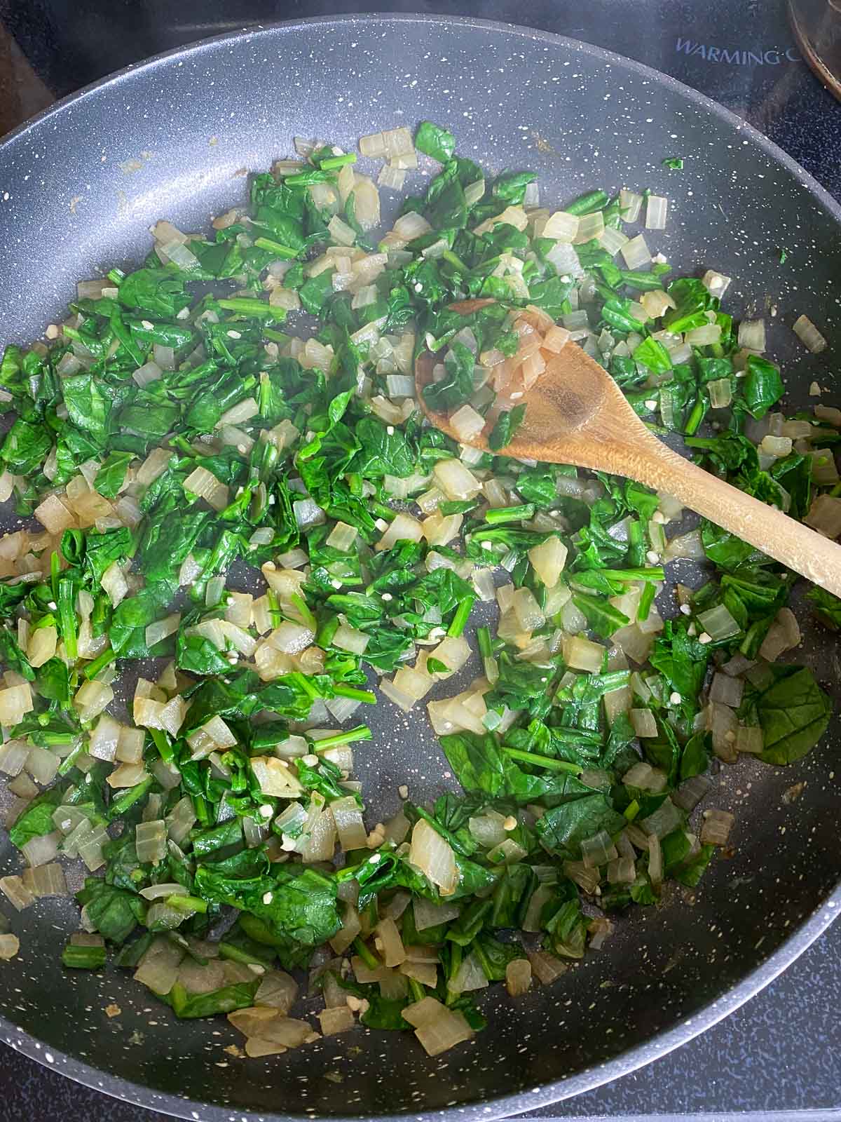 Spinach added to pan of sauteed onions.