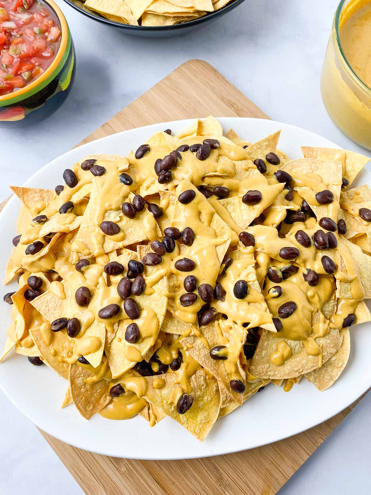 Third layer of tortilla chips, cheese sauce, and black beans on nacho platter.
