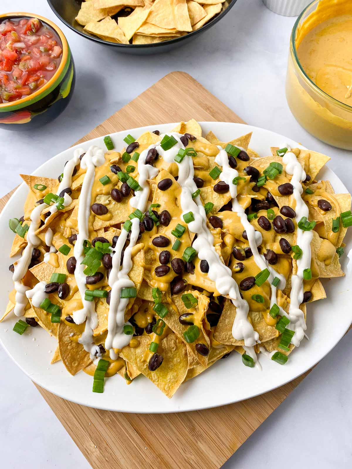 Sour cream and green onions added to platter of nachos.