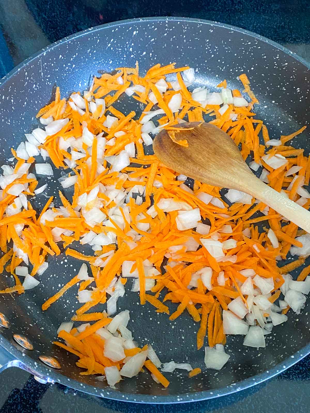 Diced onions and grated carrots in a non-stick skillet.