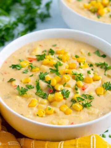 Corn chowder in a white bowl with yellow napkin.