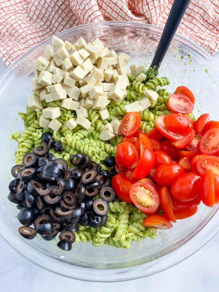 Bowl of pesto pasta salad ingredients before mixing together.