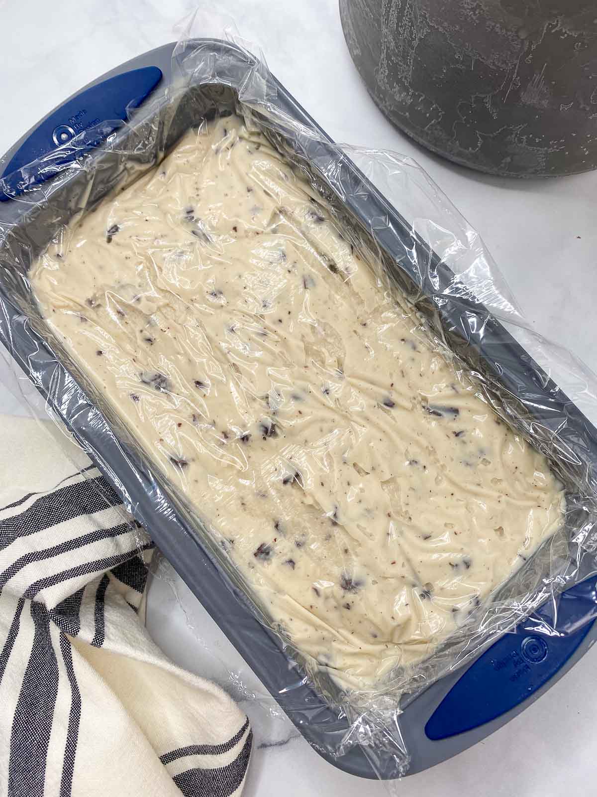 Plastic wrap over ice cream in silicone bread pan.