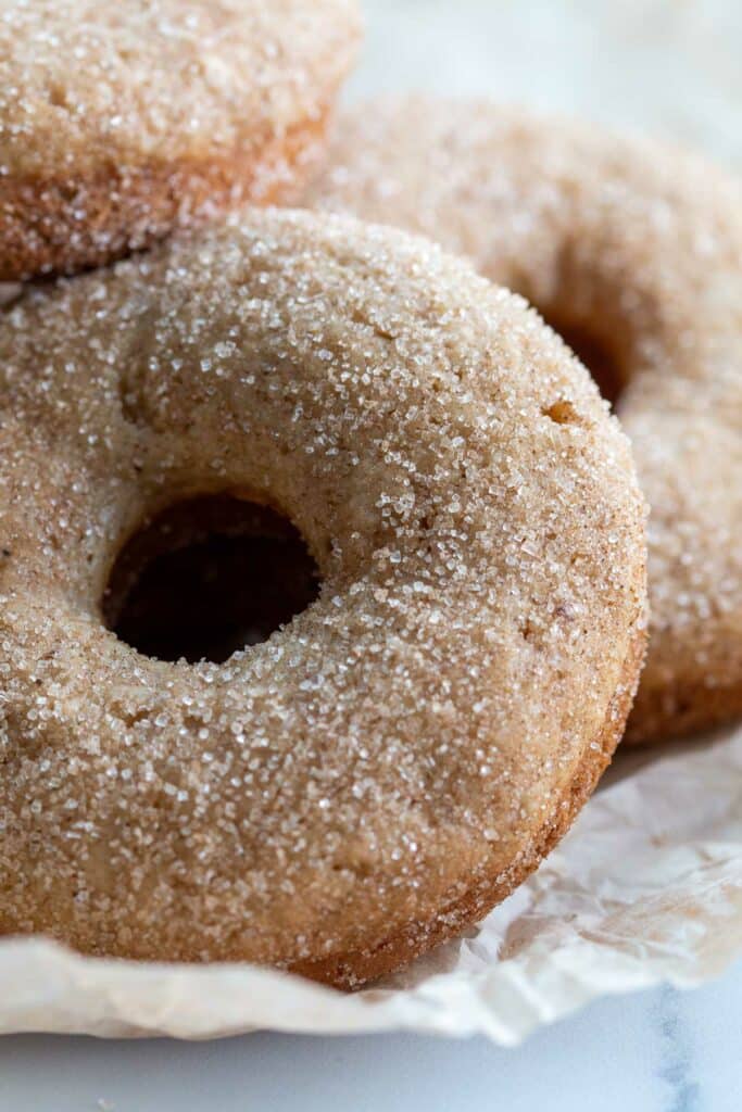 Closeup image of cinnamon sugar donuts on a piece of parchment paper.