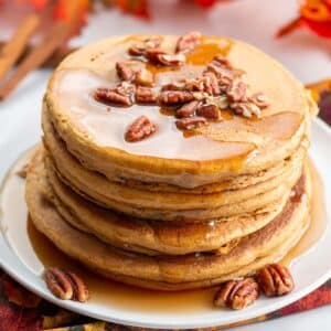 Stack of pecan topped pancakes with maple syrup.