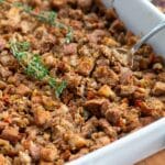 Stuffing and a spoon in a white baking dish.