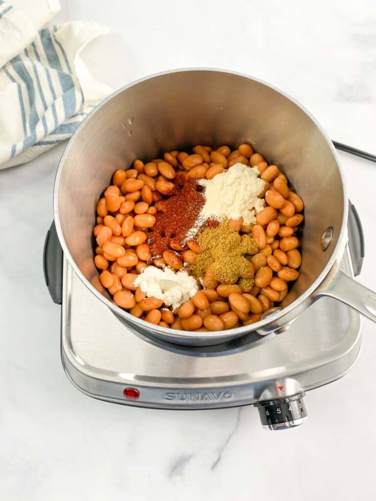 Beans and spices in a pot on a portable burner.