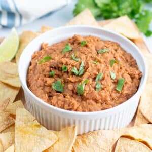 Bowl of refried beans surrounded by tortilla chips.