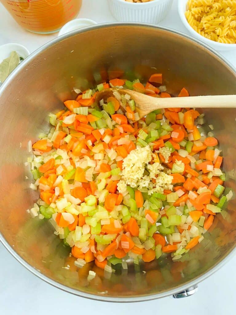 Garlic added to sauteed vegetables in large pot.