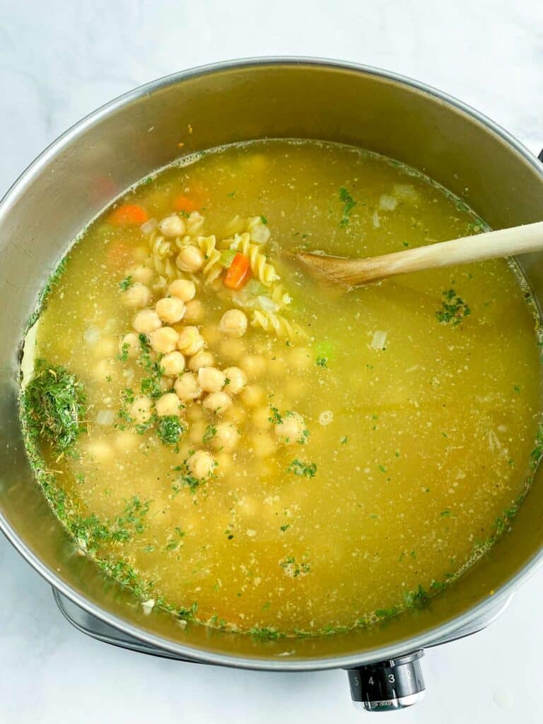 Uncooked chickpea noodle soup in a large stainless steel pot.