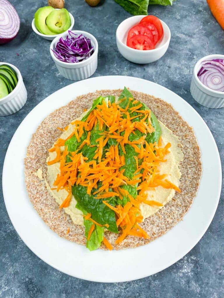 Lettuce and shredded carrots added to hummus wrap.