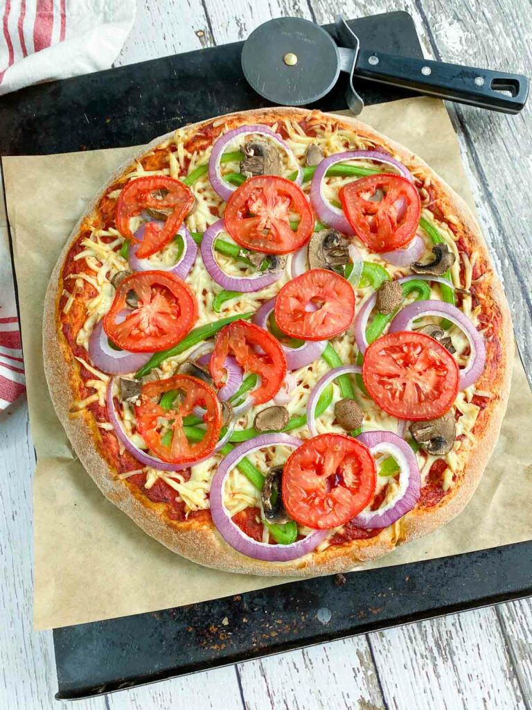 Vegetable pizza on a parchment lined pan.