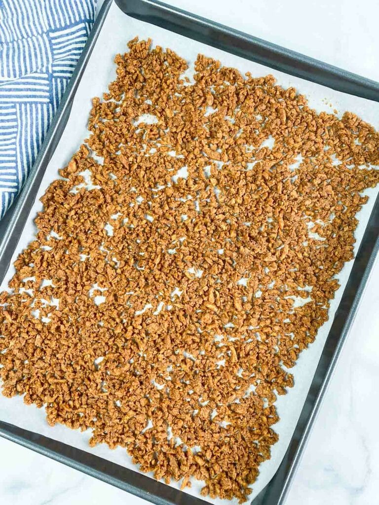 Unbaked vegan bacon bits on a parchment lined baking sheet.