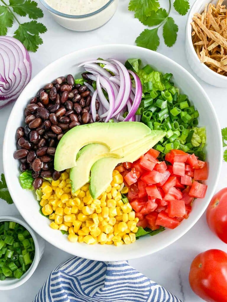 Overhead shot of southwest salad without dressing, and salad ingredients surrounding it.