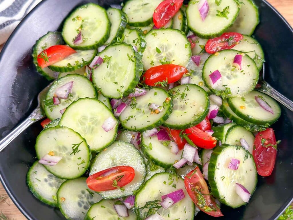 Closeup image of cucumber salad in a black bowl.