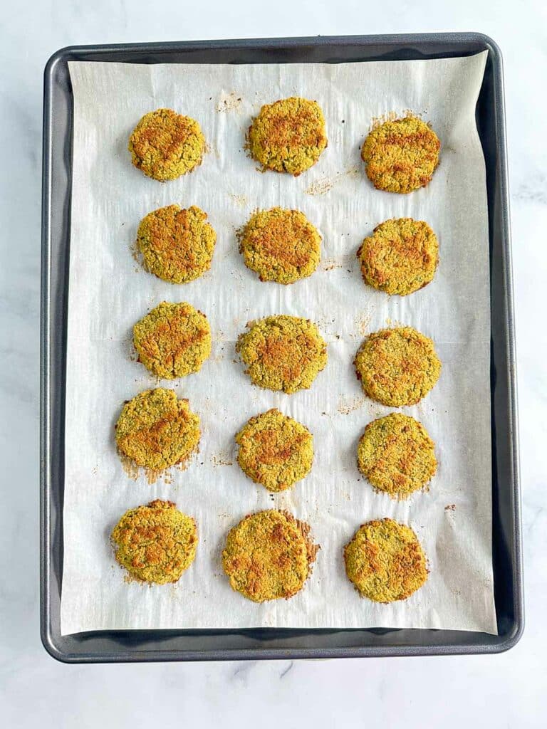Baked falafel on a parchment lined baking sheet.