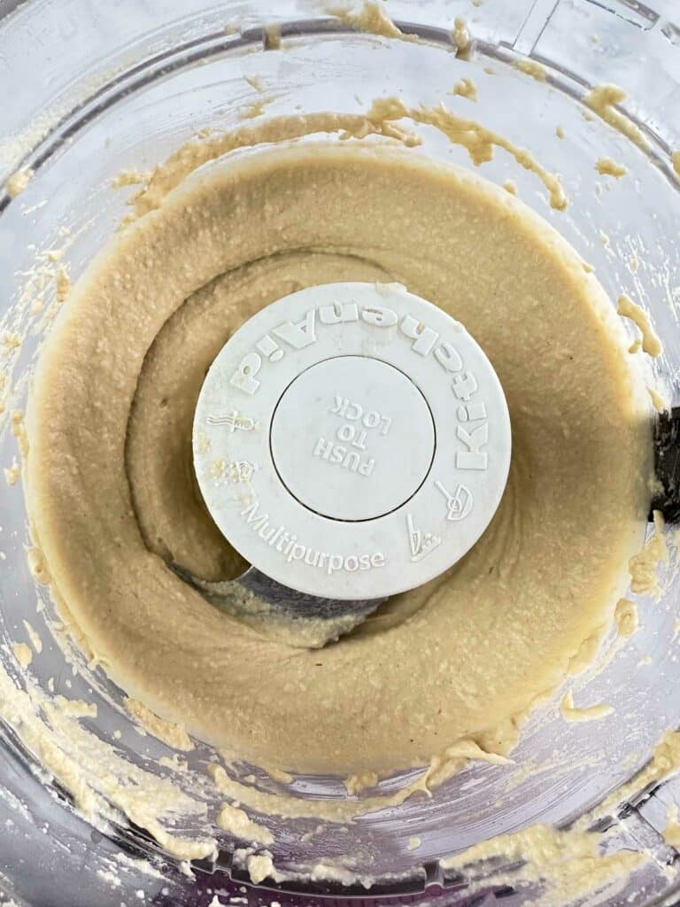 Blended hummus in food processor bowl.