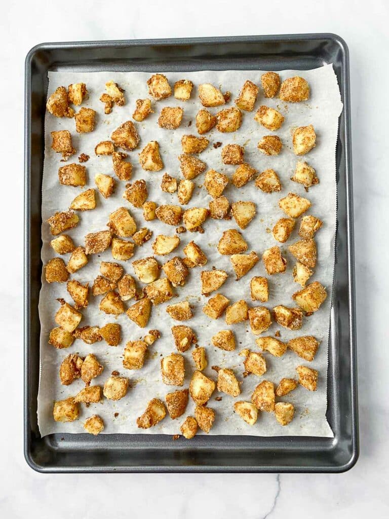 Baked crispy potato bites on a parchment lined baking sheet.