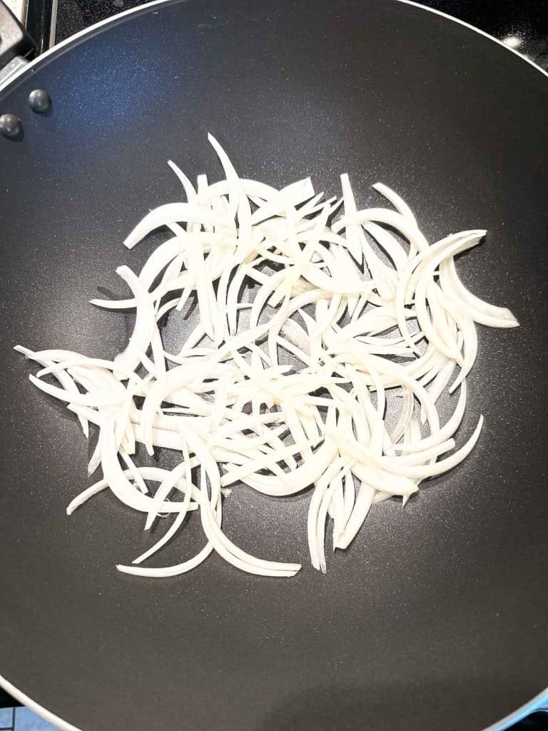 Sliced onions in a nonstick wok.