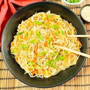 Overhead shot of vegan teriyaki noodles in a black bowl with chopstick in the bowl.