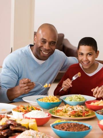 Family happily enjoying a meal together around their table with options for vegan and non-vegan family members.