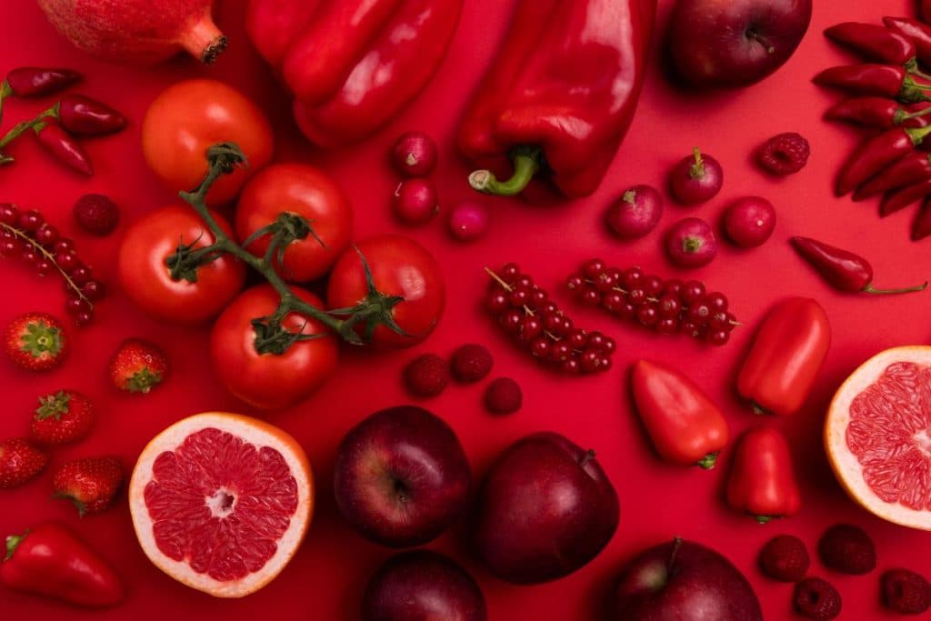 Variety of red fruits and vegetables on a red background.